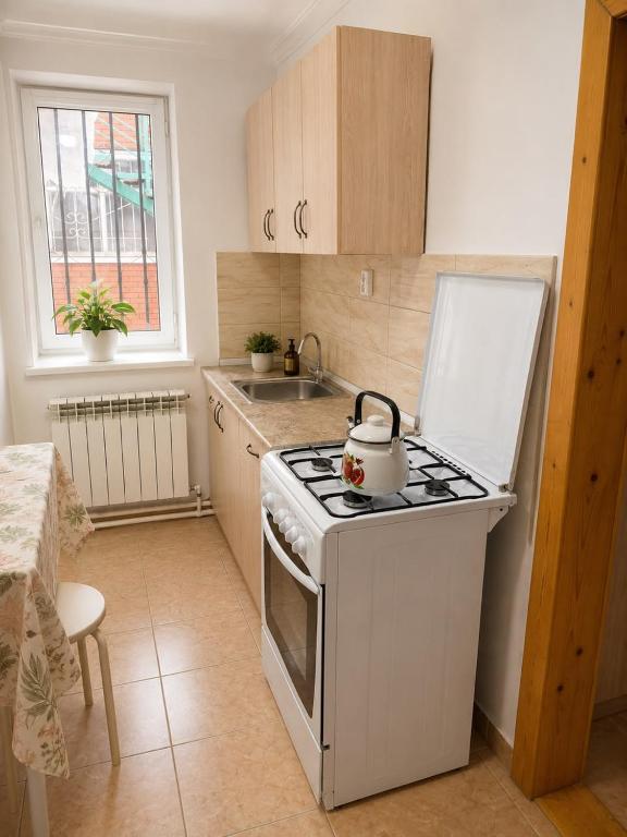 a kitchen with a stove with a tea kettle on it at Гостевой дом Москва in Aktobe