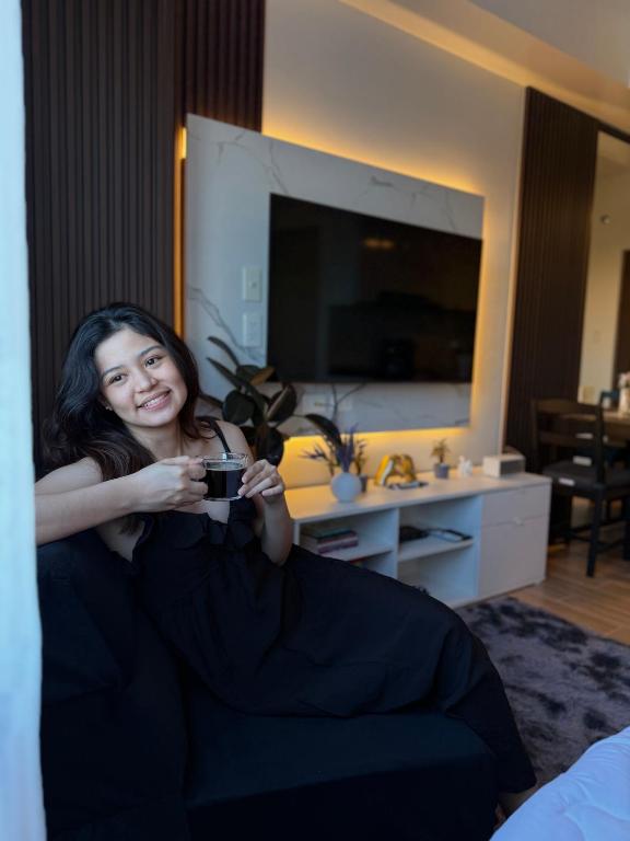 a woman sitting on a couch holding a camera at Maison Angela Suites in Biñan