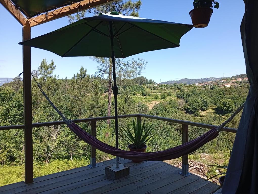 a hammock on a deck with a green umbrella at Cabana do Gipsy in Ponte da Barca