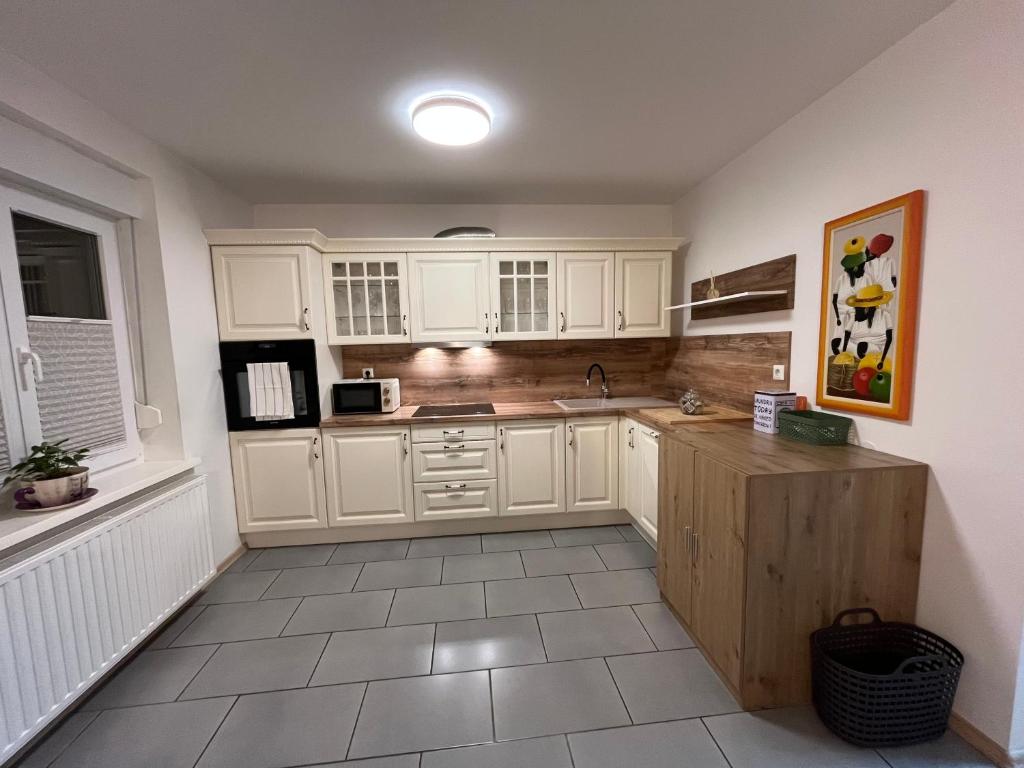 a kitchen with white cabinets and a sink and a microwave at Hiša Čebron in Podnart