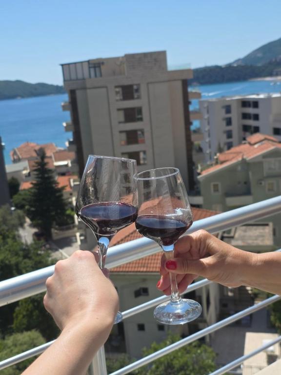 two people holding glasses of wine on a balcony at Rafailovici Sea View in Rafailovici