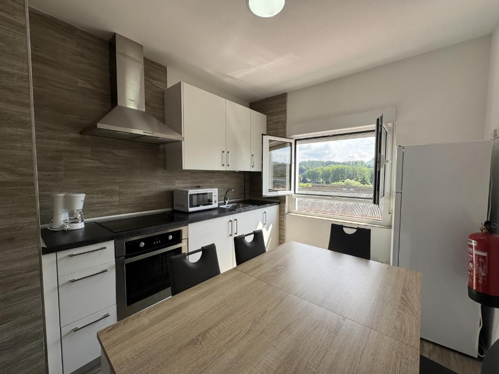 a kitchen with white cabinets and a wooden table at Alojamiento Picos de Europa VUT-2458-AS in Arriondas