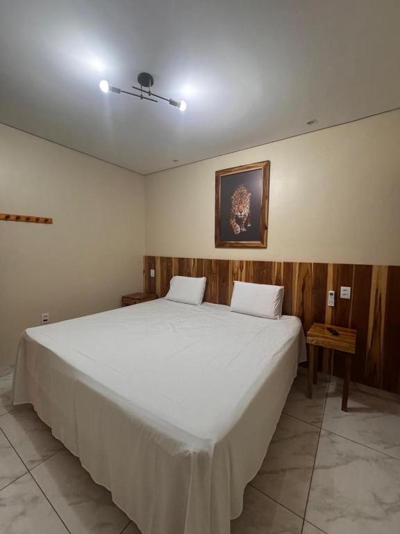 a bedroom with a large white bed in a room at Pousada Safari do Jaguar in Poconé