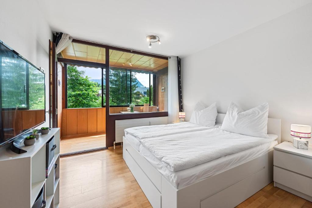 a bedroom with a white bed and a large window at Riverview Apartment - Bad Aussee in Bad Aussee