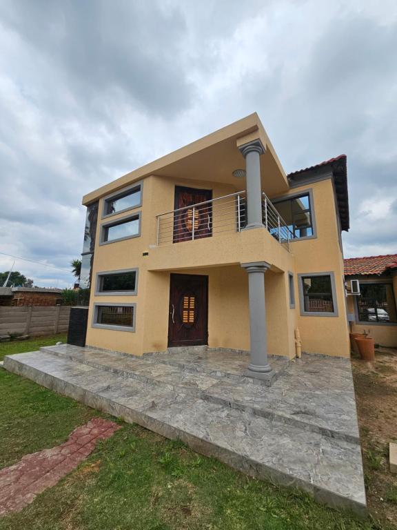 a large yellow house with a balcony at Posimuma in Centurion