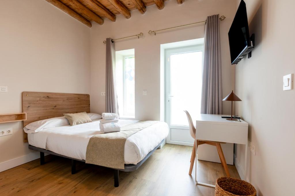 a bedroom with a bed and a desk and a window at Hospedería Boho Granada by eme hoteles in La Zubia