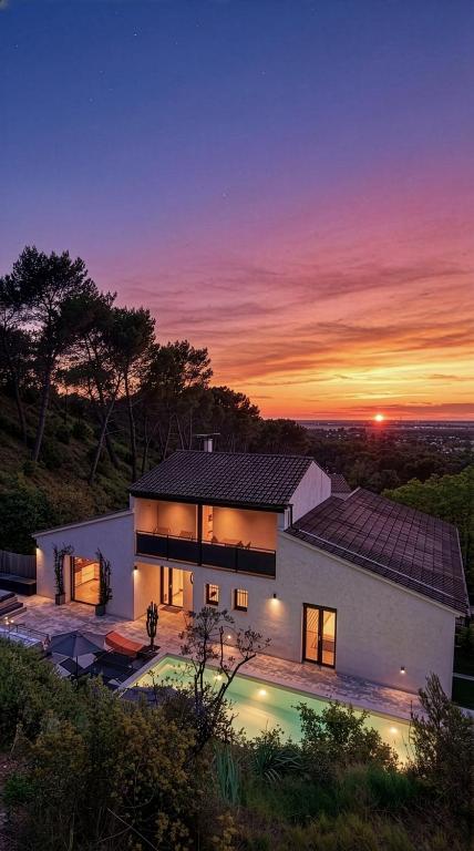 a large house with a sunset in the background at Arty Provence, vue, calme et piscine chauffée dans les Alpilles proche St-Rémy-de-Provence in Saint-Étienne-du-Grès