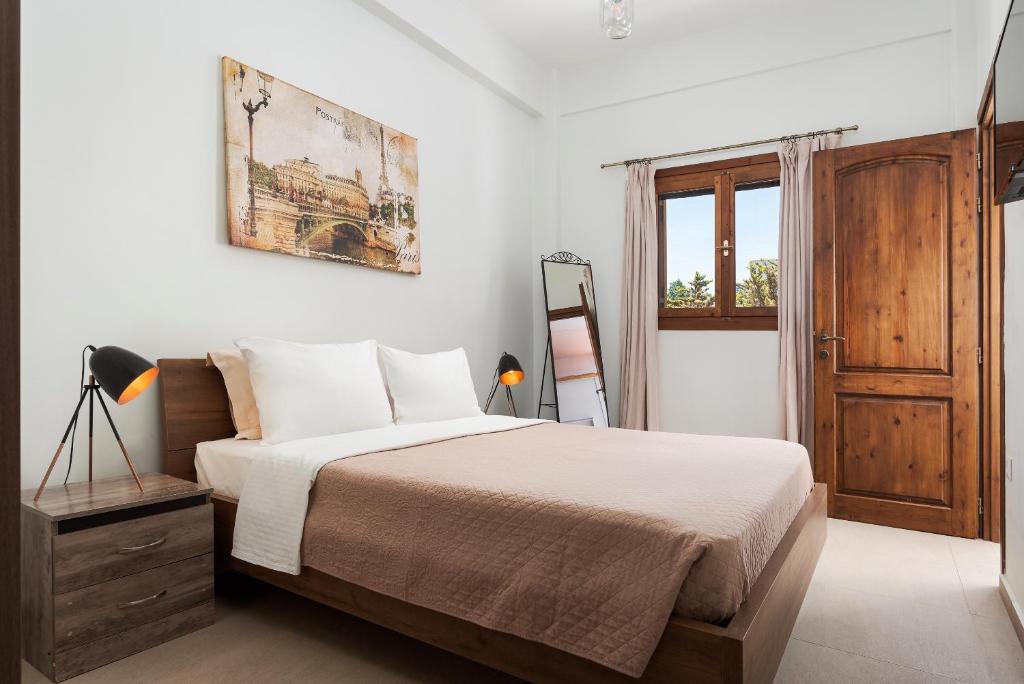 a white bedroom with a bed and a window at Utopia Suites in Egina