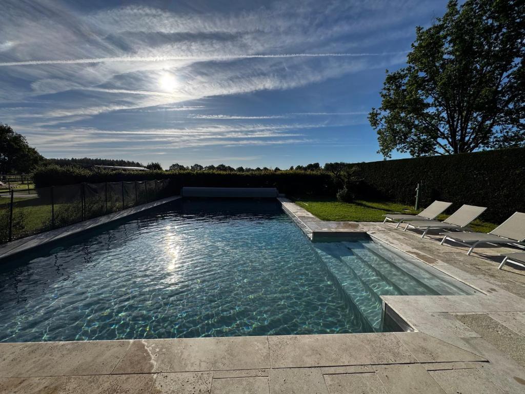 a swimming pool with two chairs in a yard at Les gîtes de la Grange de Léonie - jacuzzis privatifs et Piscine in Vierzon