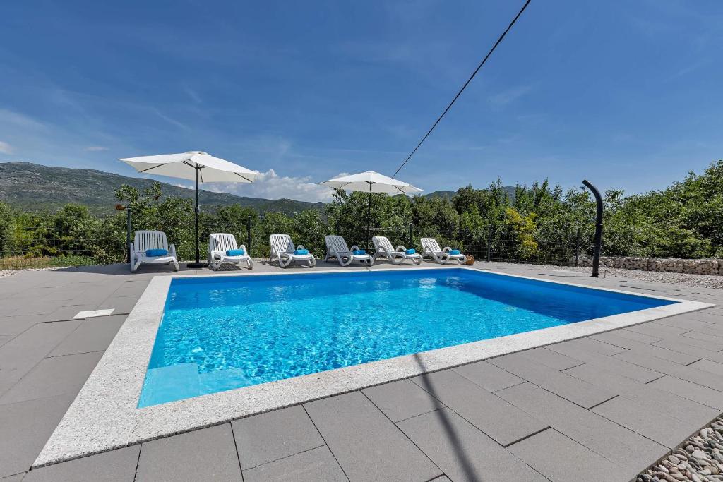 a swimming pool with some chairs and umbrellas at Villa Magdalena in Zavojane