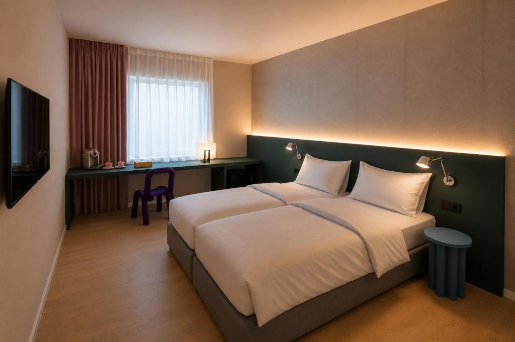 a hotel room with a bed and a desk at Hôtel Les Loges in Geneva