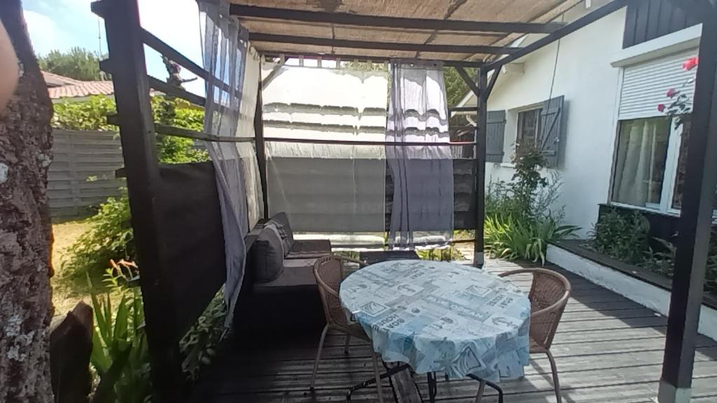 a patio with a table and chairs on a deck at Maisonnette mitoyenne andernos in Andernos-les-Bains