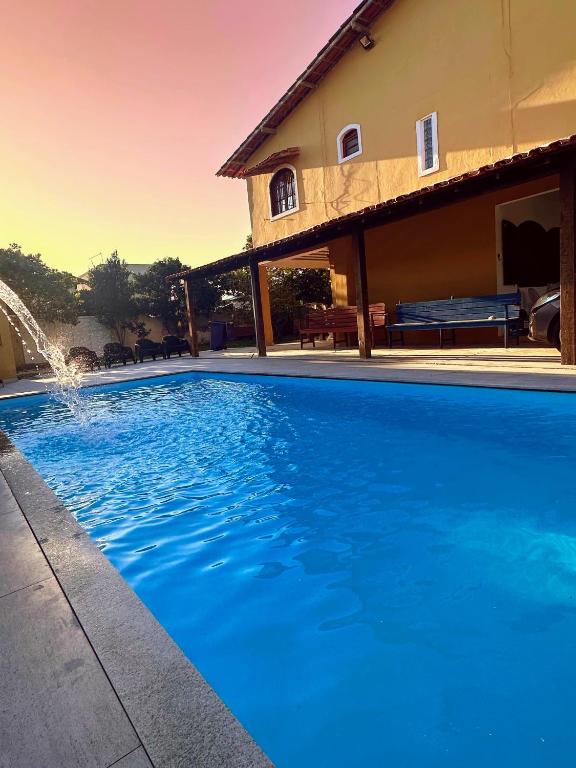 a large blue swimming pool in front of a house at Casarão entre Cabo Frio e Búzios Piscina Privativa Ar condicionado, Sinuca, Totó, Churrasqueira 4 quartos Wi-Fi 500mb in Cabo Frio