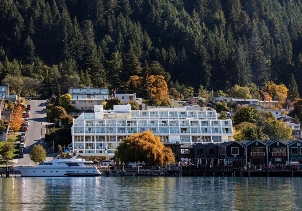 a hotel on the shore of a lake with a boat at Crowne Plaza Queenstown by IHG in Queenstown