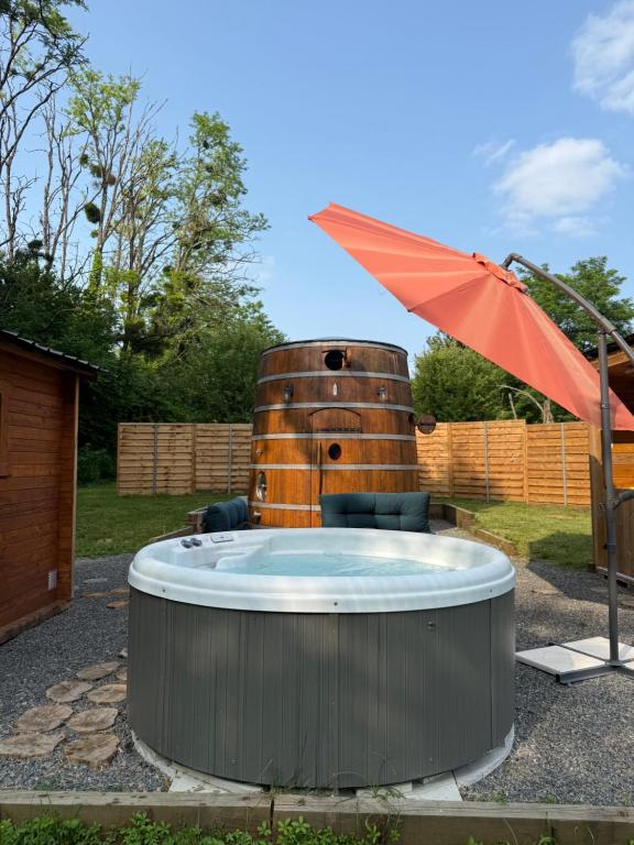 a hot tub in a yard with an umbrella at Foudre Insolite in Naujan-et-Postiac