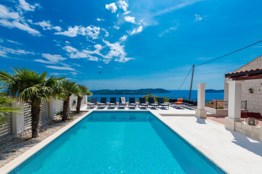 a swimming pool with chairs and palm trees on a building at Villa Konstantina in Orasac