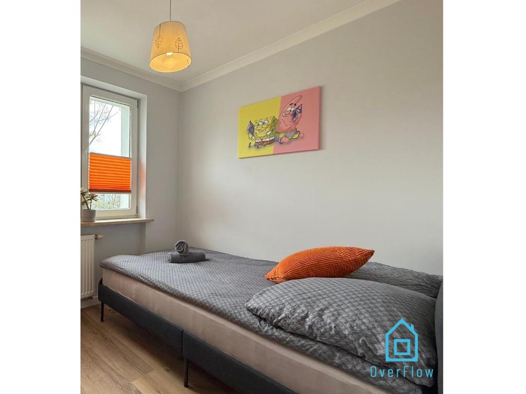 a bedroom with a bed with an orange pillow at Spongebob Room 10 Min to Old Town Gdańsk,PKP & Shopping Mall in Gdańsk