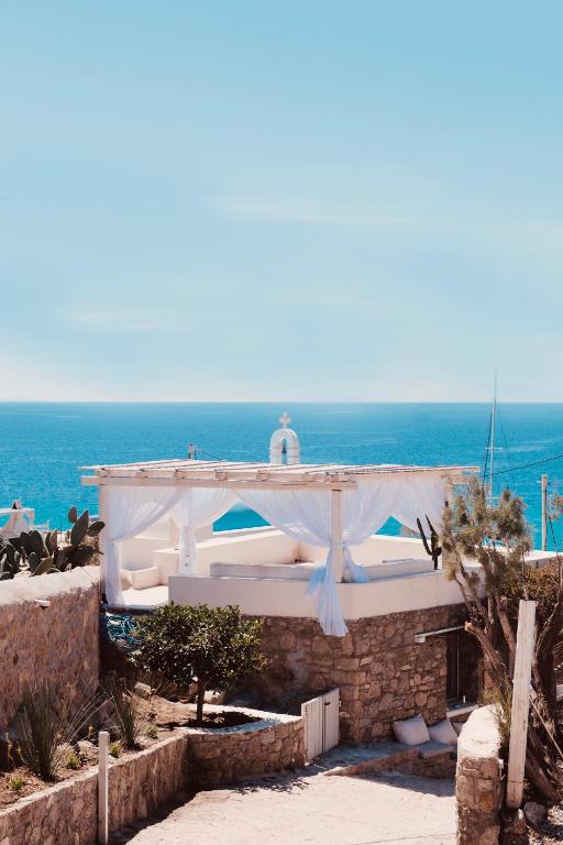a white building with the ocean in the background at myMykonos Guest House in Platis Gialos