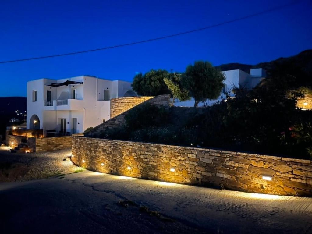 a house with a stone wall and lights at night at IosAgnanti in Ios Chora