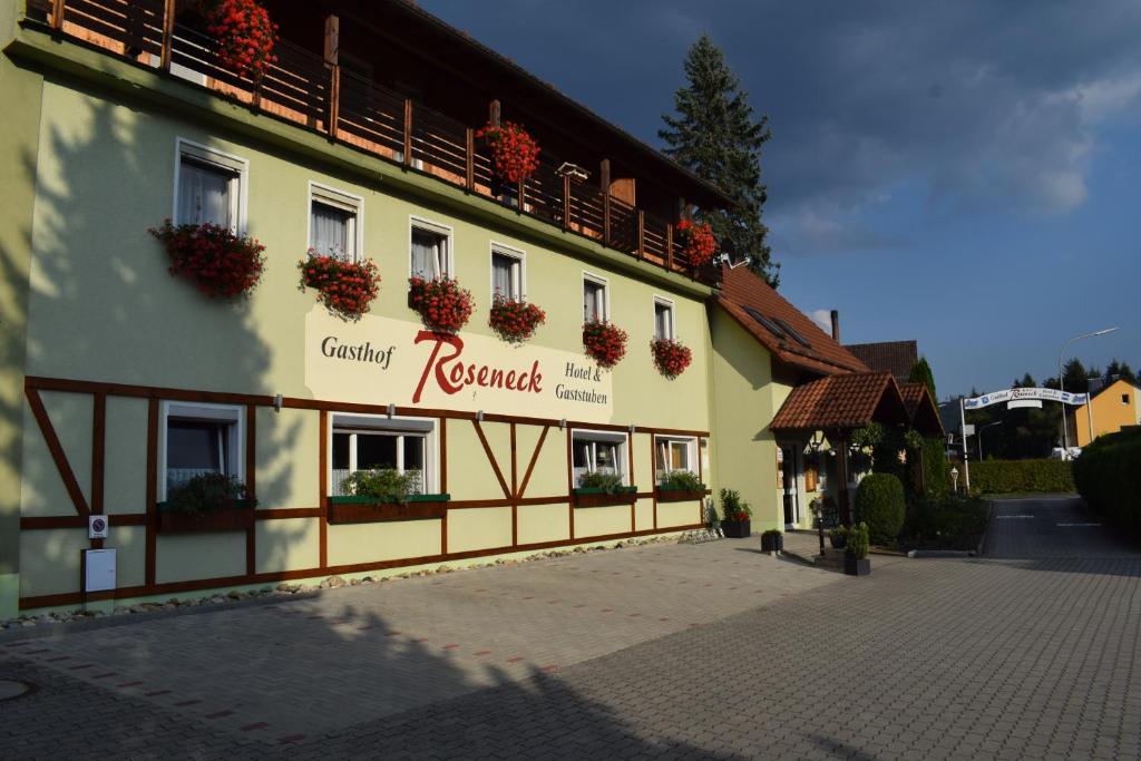 un bâtiment avec des boîtes de fleurs sur son côté dans l'établissement Gasthof Roseneck, à Wallenfels