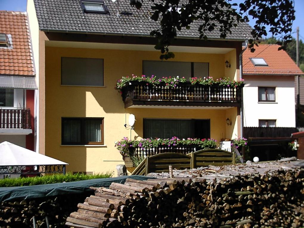 a yellow house with a balcony with flowers on it at Haus Moser in Wildensee