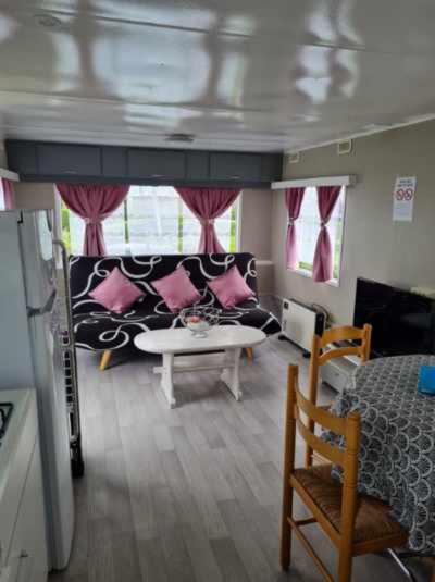 a room with a bed and a couch and a table at Mobilhome empl 28 in Saint-Martin-aux-Buneaux