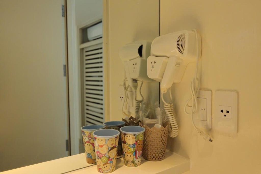 a hair dryer and cups on a shelf in a bathroom at Tuệ House in Ấp Gia Thanh (1)