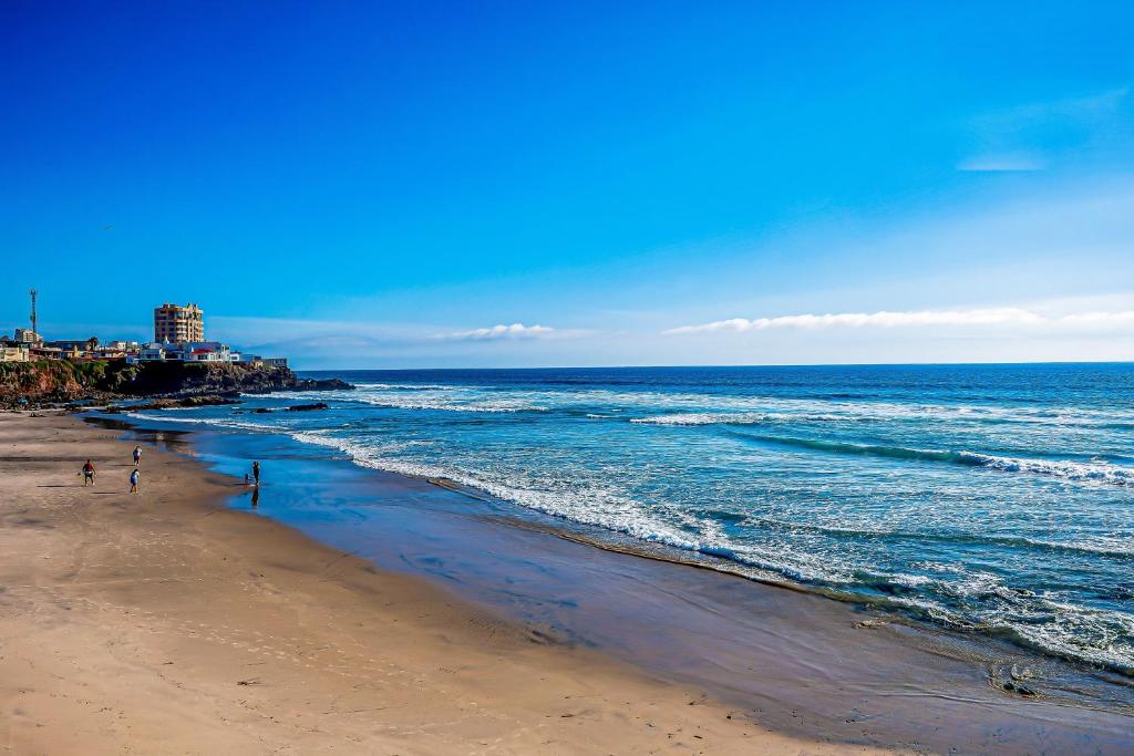 a beach with people walking on the sand and the ocean at Airy, Beach-View Dog-Friendly Villa with Patio, Outdoor Pool, Streaming, AC in Rosarito