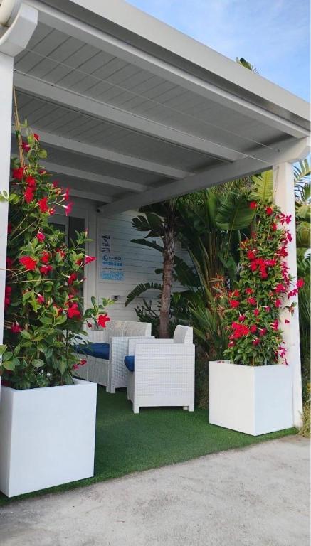 a patio with white furniture and red flowers at AURORA BEACH & SUITE in Margherita di Savoia