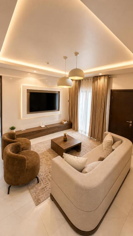 a living room with a couch and two chairs and a television at The Luxe Cottage in Ikeja