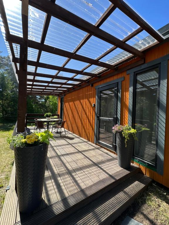 a pergola on a deck with a table and chairs at Dimantu nami in Upesgrīva