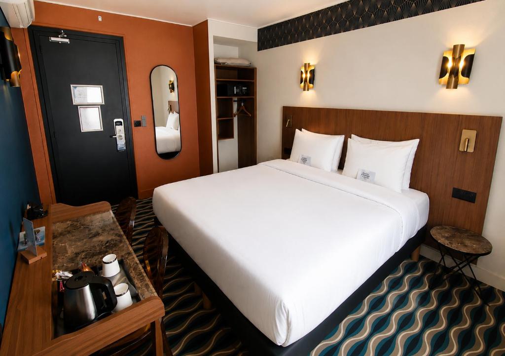 a bedroom with a large white bed in a room at Kyriad Hotel XIII Italie Gobelins in Paris