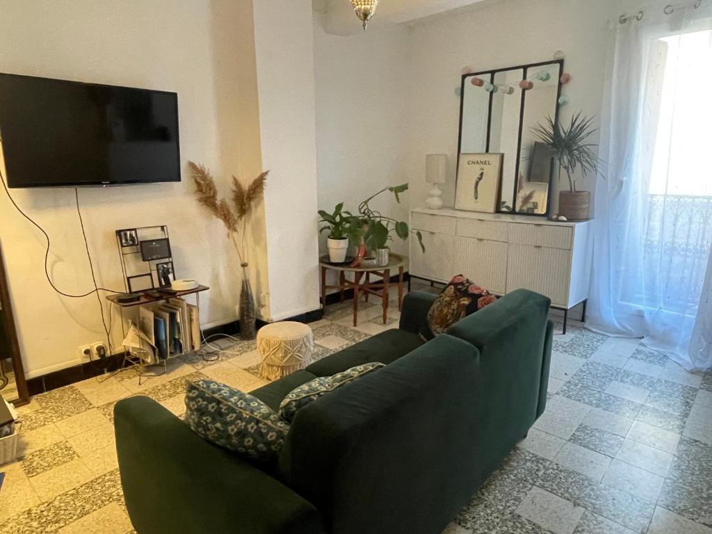 a living room with a green couch and a tv at Giovanna in Marseillan