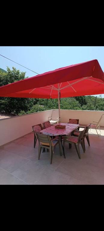 a table with a red umbrella on a patio at Nensi1 in Križišće