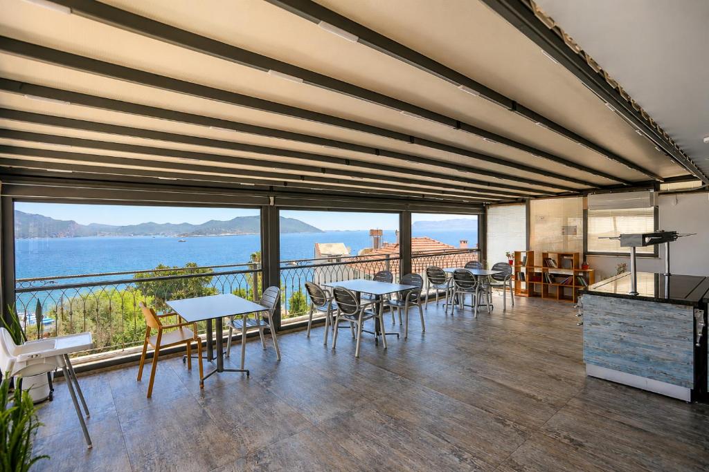 a room with tables and chairs and a view of the water at Payam Agora Hotel Room Only , Shared Terrace & Kitchen in Kaş