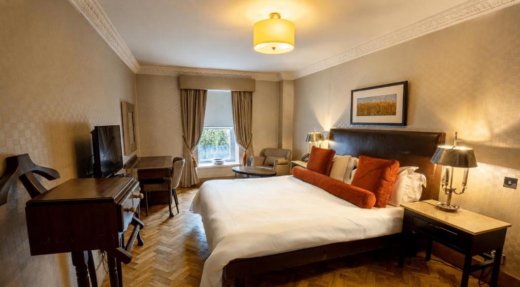 a hotel room with a large bed and a desk at Langtons Hotel Kilkenny in Kilkenny