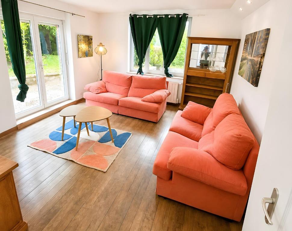 a living room with two orange couches and a table at L'échappée Verte en Thiérache in Martigny