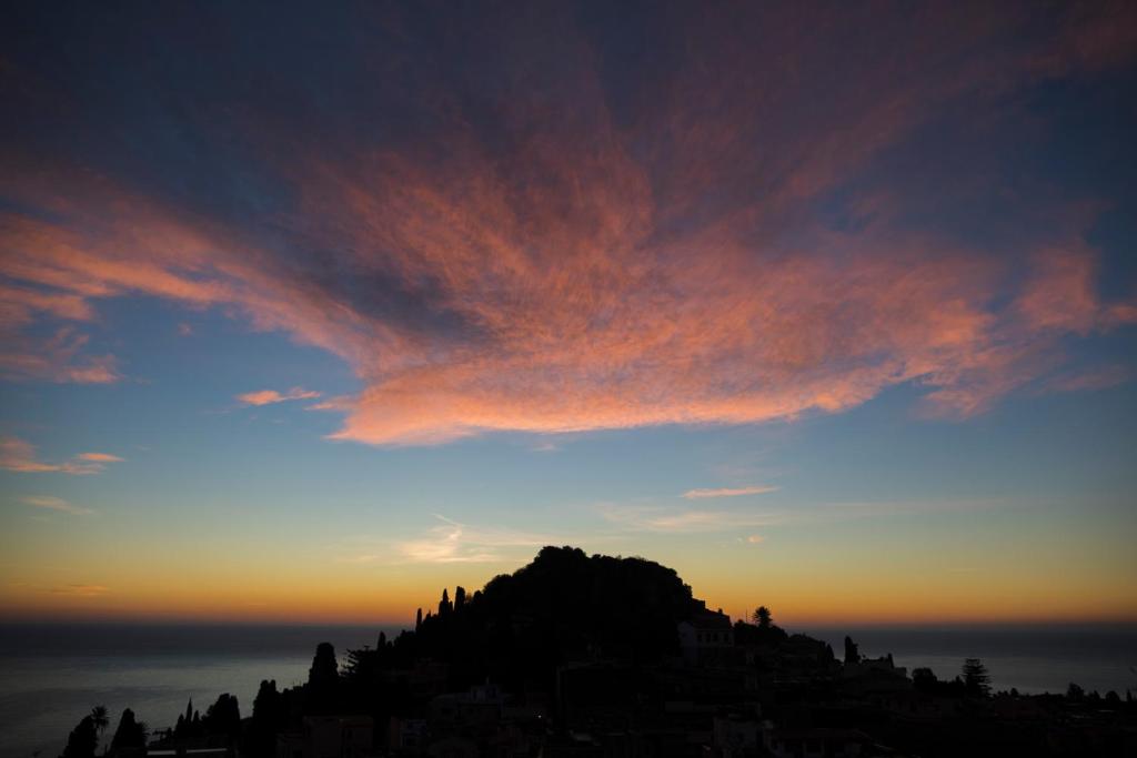 einen Sonnenuntergang mit einer Wolke über einem Berg in der Unterkunft Tauromenion Guest House in Taormina