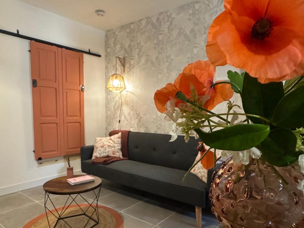 a living room with a couch and a vase with flowers at Résidence le 1564 Terracotta in Roussillon en Isere