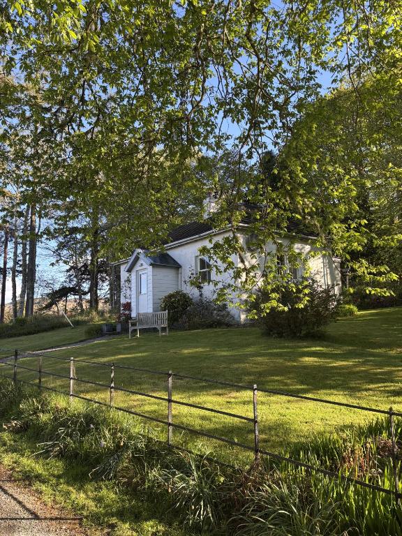a white house on a lawn with a fence at South Lodge in Lochgilphead