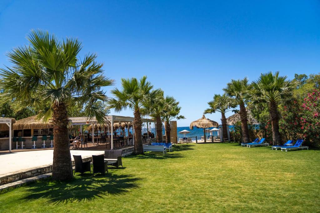 a park with palm trees and benches and a resort at Ladonia Hotels Zemda in Gümüşlük