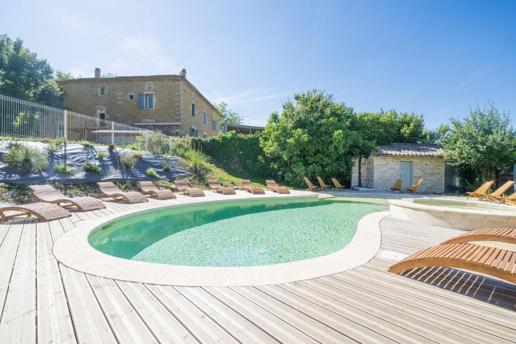 a swimming pool with chaise lounge chairs and a swimming poolvisor at Le Mûrier - Grospierres in Grospierres