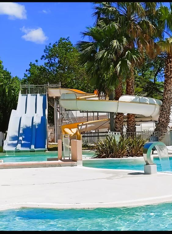 a pool with a water slide at a resort at Mobil home 6 personnes confort Océan climatisé camping avec piscine Agde in Agde