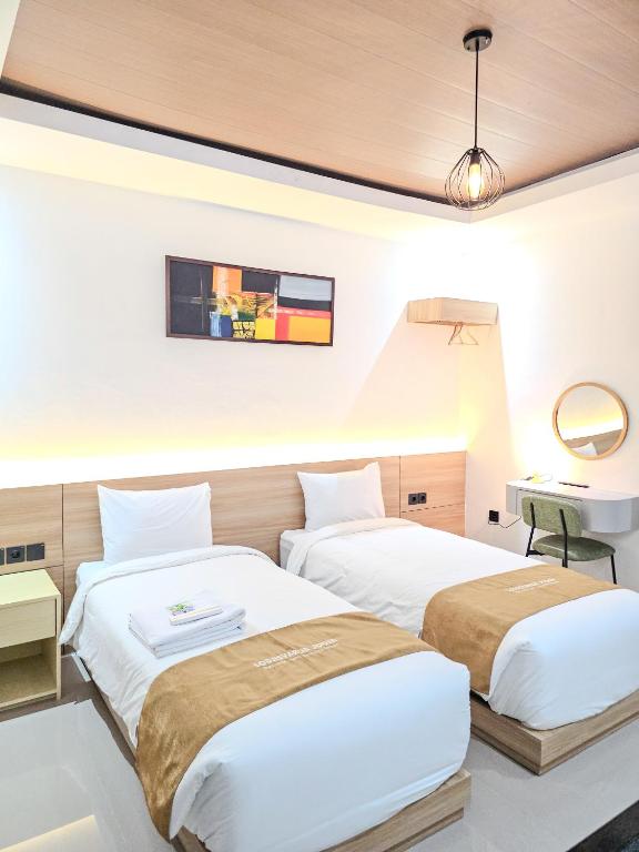 a bedroom with two beds and a mirror at Lodjisvarga Villa Yogyakarta in Sleman
