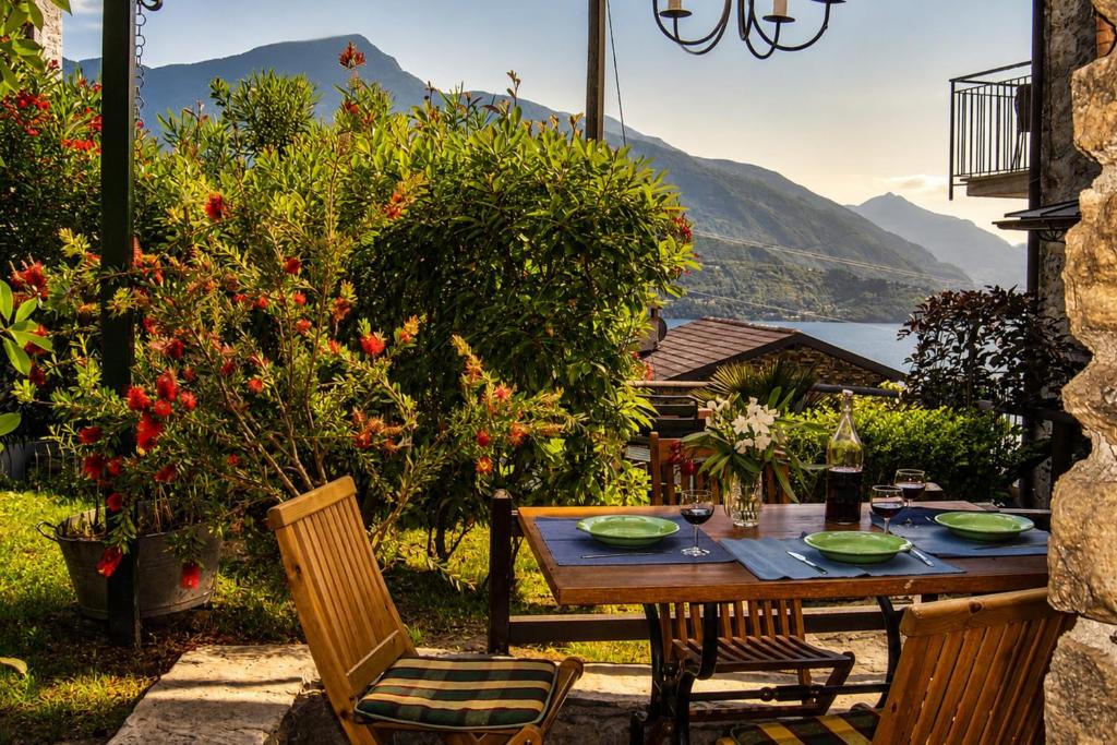a wooden table and chairs in a garden with mountains at Trebbiano Rubicone in Gravedona