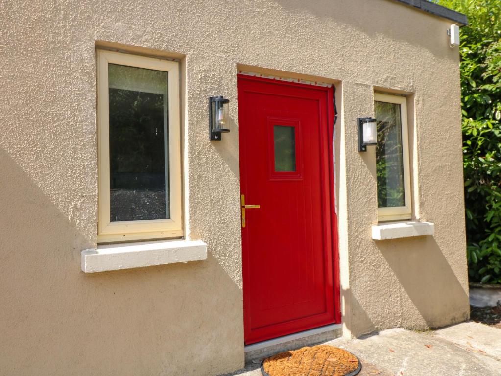 a red door on a house with two windows at The Mews Suskar in Glendarragh