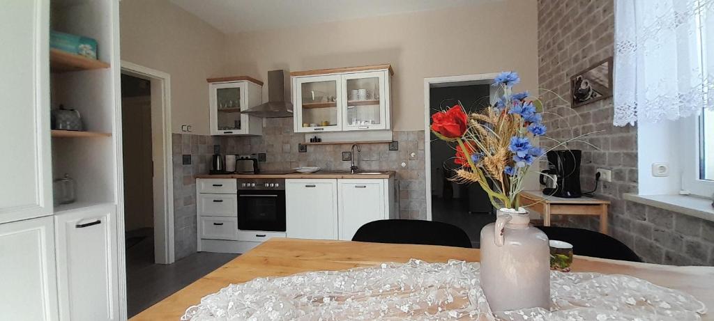 a kitchen with a table with a vase of flowers at Sandstein-Oase in Reinhardtsdorf
