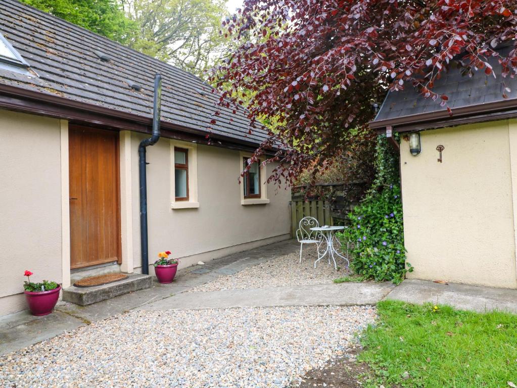 a house with a table and a chair in front of it at The Mews Derrybawn in Glendarragh