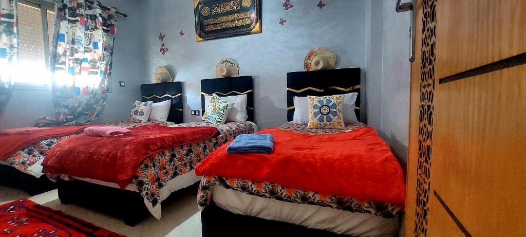 a bedroom with two beds with red sheets at Apprt Ennakhil 2 in El Jadida