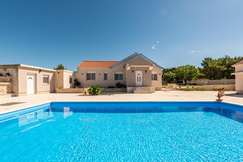 a large blue swimming pool in front of a house at Holiday Home Marija with pool in Buković